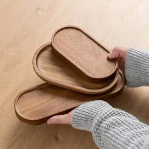Hands in a knit sweater holding two oval wooden serving trays as artisanal slow living kitchen accessories