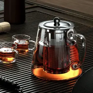Glass teapot in a complete tea ceremony setup with small cups and warming stand for an aesthetic home tea ritual display